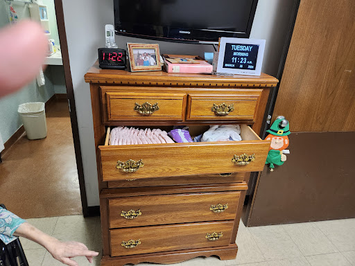 A wooden dresser with several drawers, partially opened to reveal neatly folded clothes.