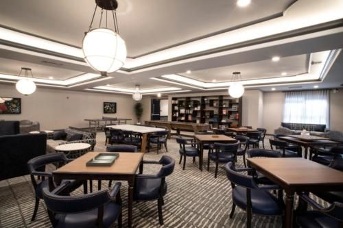 A modern dining area with neatly arranged tables and chairs, illuminated by elegant ceiling lights.
