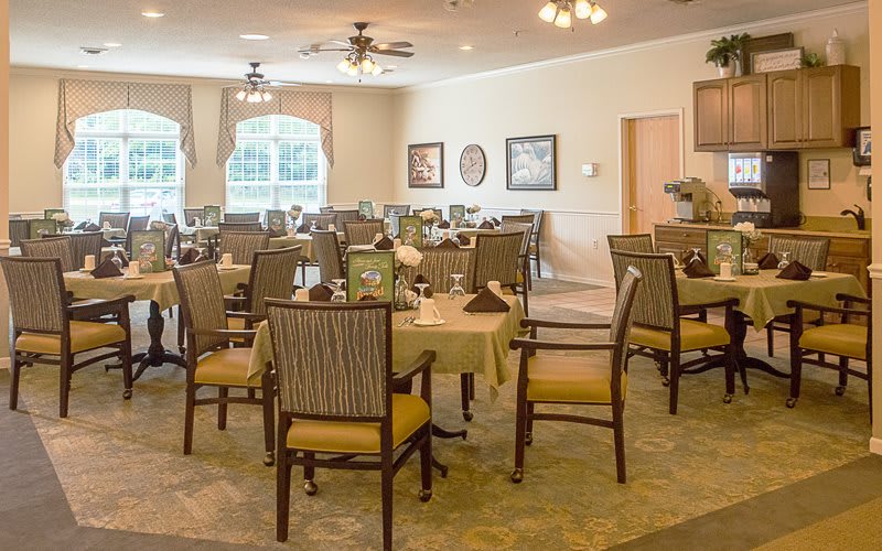 A well-set dining room with multiple tables and chairs, featuring elegant decor and ambient lighting.