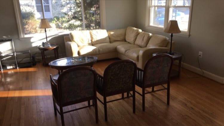 A sunlit living room with a beige sofa, several chairs, and a coffee table.