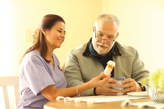 A nurse assists a senior man with his medication.