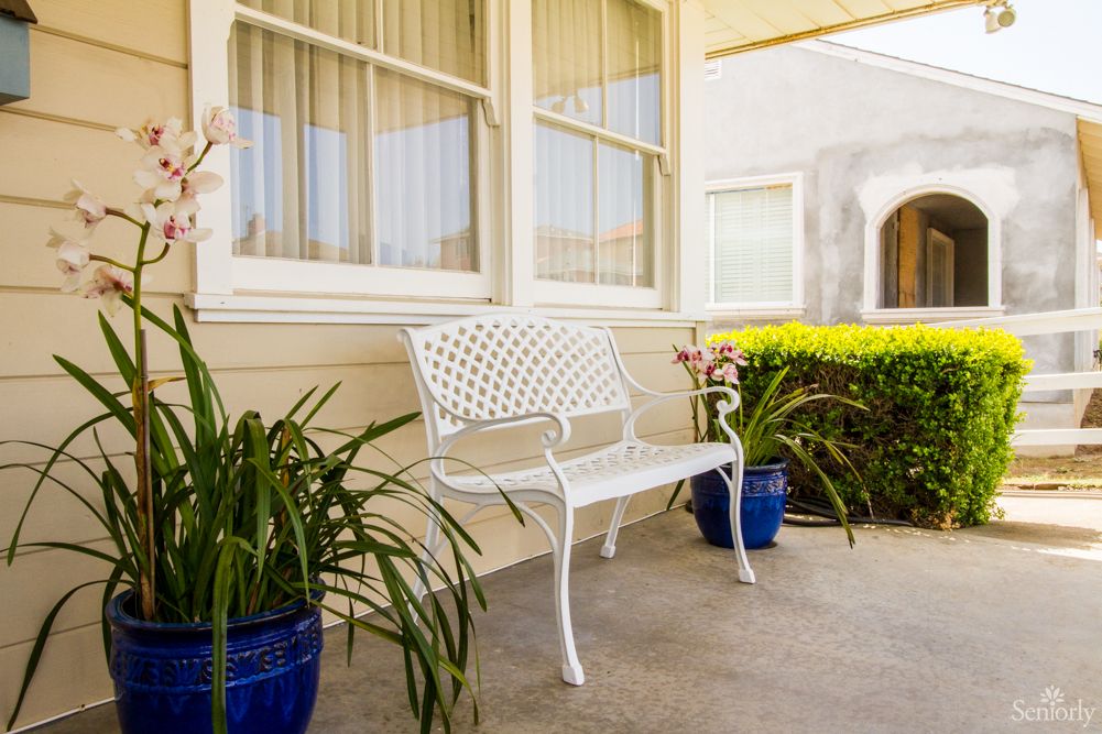 A quaint porch with a white bench and potted plants.