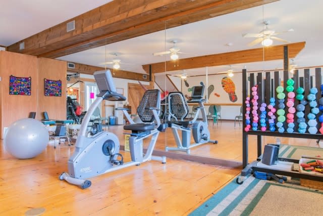 A well-equipped gym featuring exercise bikes, mirrors, and a rack of dumbbells.