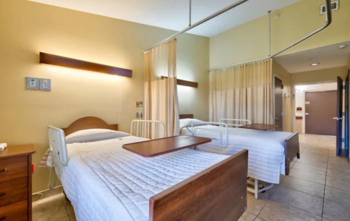 A hospital room with two beds separated by privacy curtains.