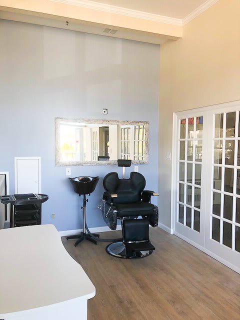 A well-lit salon interior featuring a barber chair, large mirror, and hairdressing equipment.