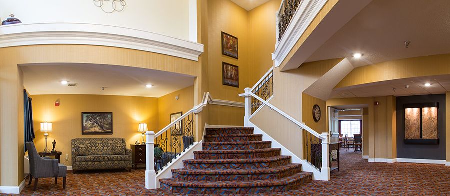 A cozy hotel lobby featuring a carpeted staircase with elegant railings and warm lighting.
