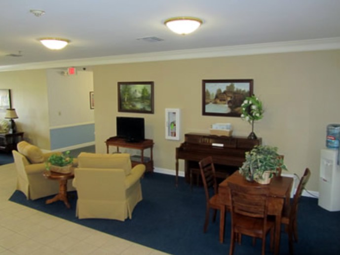 A cozy indoor living space featuring a piano, chairs, a table, and paintings on the wall.