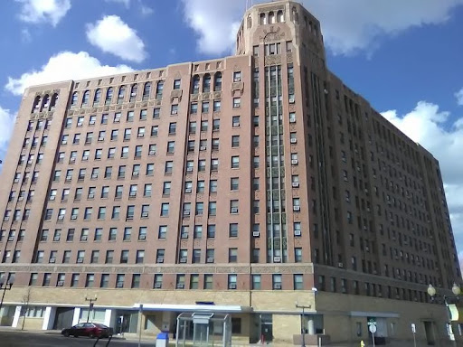 A historic brick building with a strong architectural presence against a partly cloudy sky.