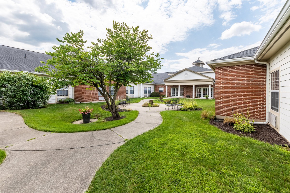 A landscaped courtyard with a winding pathway and brick buildings under a cloudy sky.