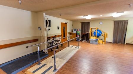 A physical therapy room equipped with parallel bars and various rehabilitation tools.