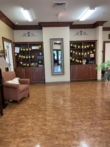 A warm and inviting lobby with wooden flooring, stylish furniture, and decorative shelves.