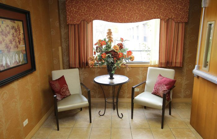 A cozy seating area with two chairs, a round table, and a floral arrangement by the window.