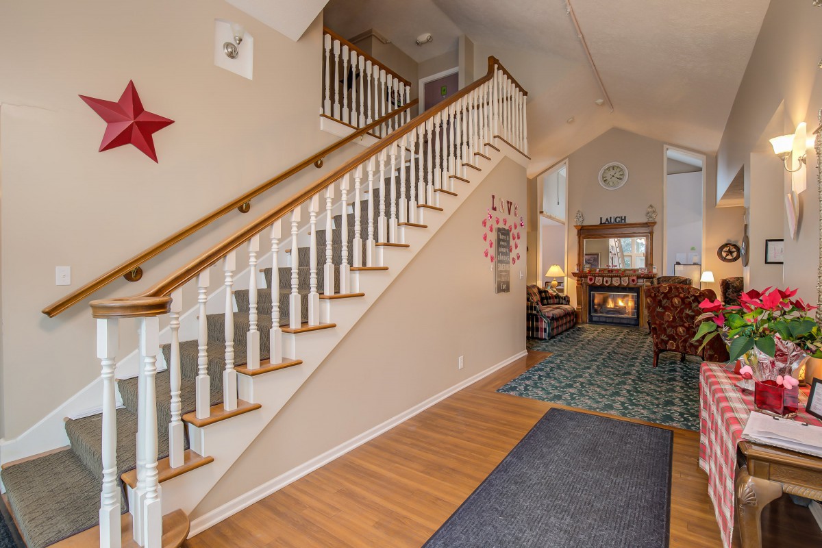 A welcoming home hallway featuring a wooden staircase with white railings and traditional decor.