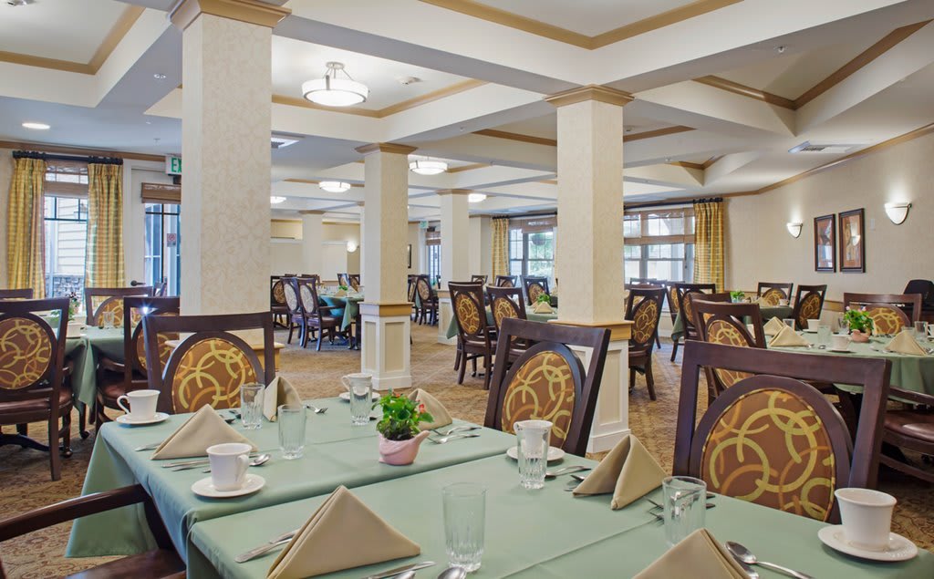 An elegantly decorated dining room with set tables and stylish chairs, ready for guests.