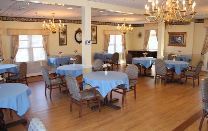 A well-decorated dining area featuring blue tablecloths and elegant chandeliers.