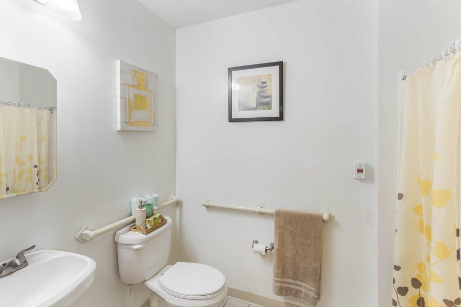 A modern minimalist bathroom with artwork and towel rack.