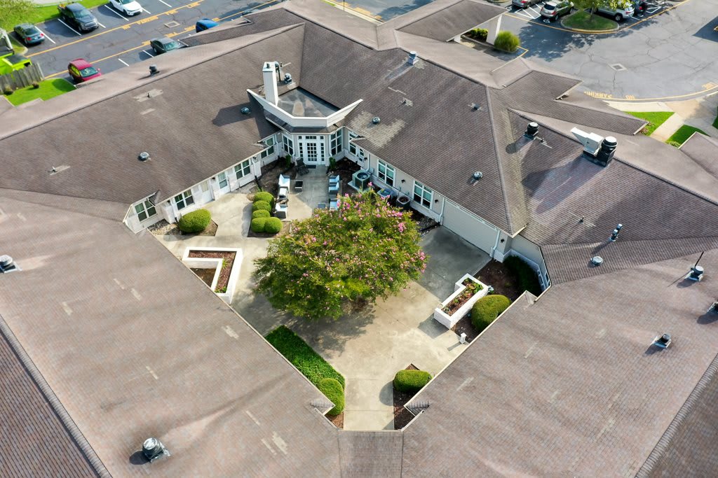 Aerial view of a building with a central courtyard featuring landscaping and a prominent tree.