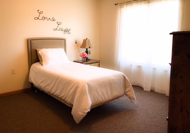 A cozy bedroom with a single bed, minimalistic decor, and soft lighting.