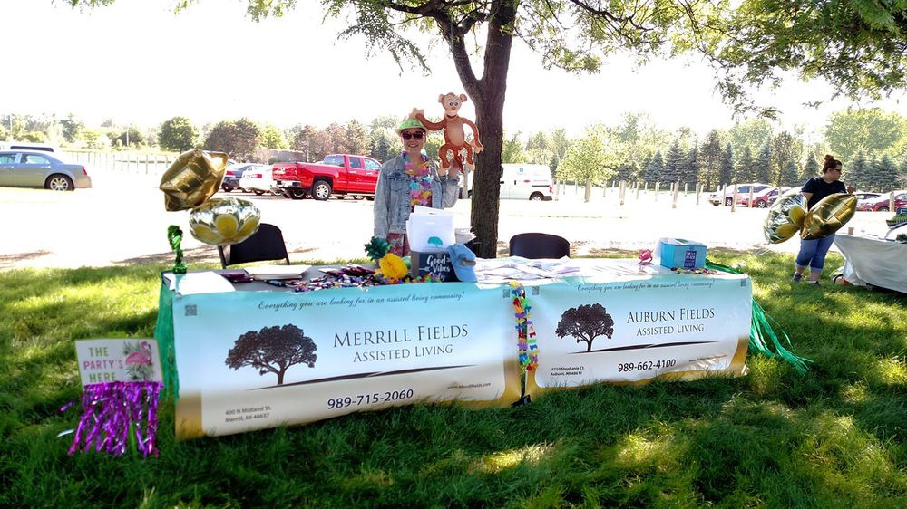An outdoor information booth set up under a tree during the day, featuring banners and materials on tables.