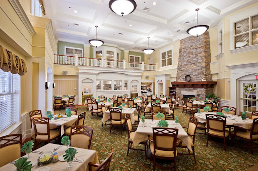 A spacious dining area featuring elegant tables and chairs, adorned with green decor, and a cozy fireplace.