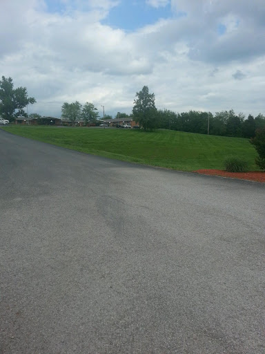 A view of a winding road leading into a grassy area under a cloudy sky.