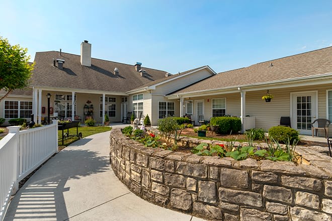 A residential building with a landscaped outdoor area featuring a stone wall and garden.