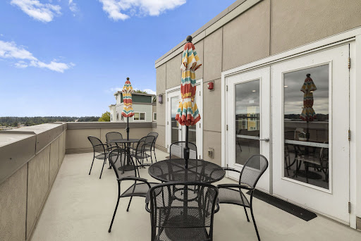 A spacious rooftop patio featuring stylish outdoor furniture, colorful umbrellas, and a bright blue sky.
