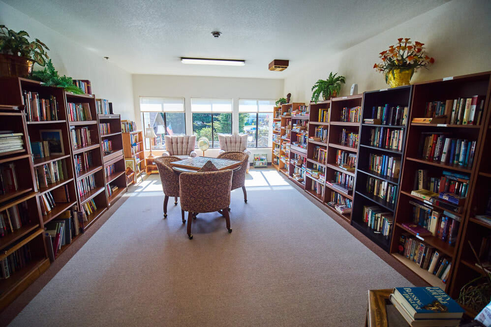A cozy library with bookshelves and a reading area bathed in natural light.
