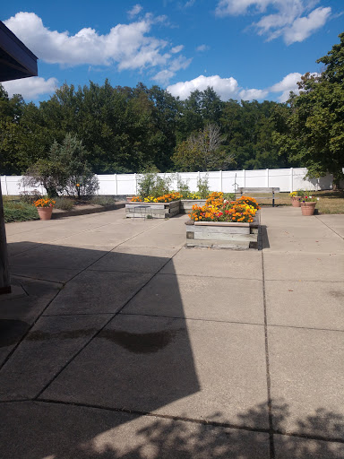 A serene outdoor space featuring colorful flowers in planters, set against a backdrop of blue skies and lush greenery.