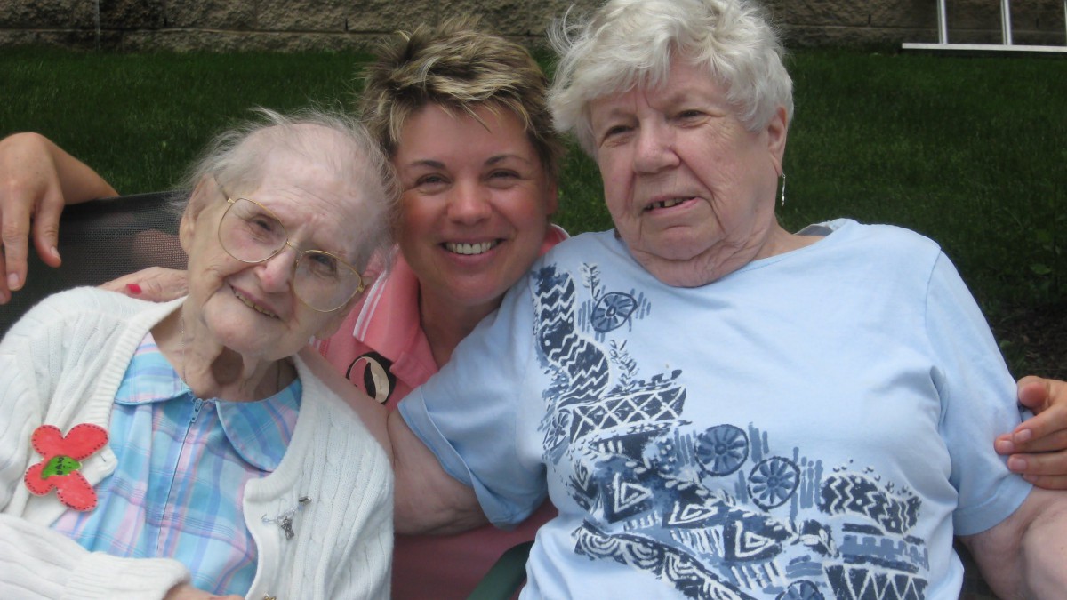 Three women sitting closely together outdoors, enjoying each other's company.