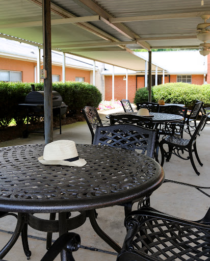 An outdoor seating area featuring black metal tables and chairs, with a white hat resting on one of the tables.