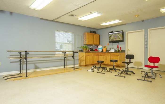 A rehabilitation room equipped with parallel bars and stools for physical therapy exercises.