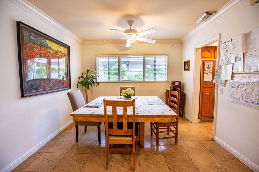 A cozy dining room with a wooden table, chairs, and artwork on the wall.