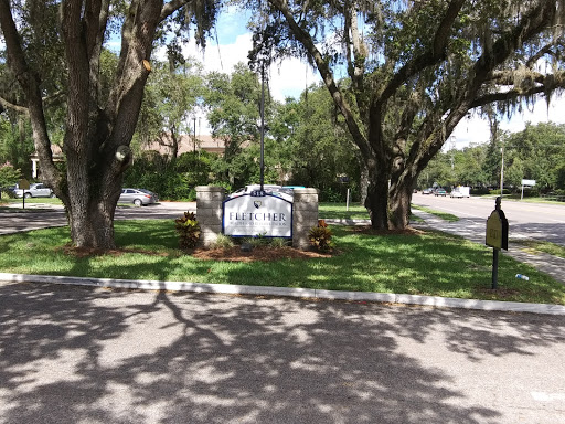 A welcoming entrance featuring a sign surrounded by lush greenery and trees.