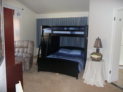 A cozy bedroom featuring a bunk bed, a recliner chair, and a small table with a lamp.