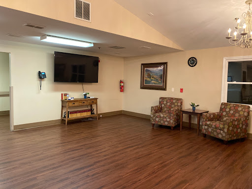 A cozy living room setup featuring comfortable chairs, a wall-mounted television, and wooden flooring.