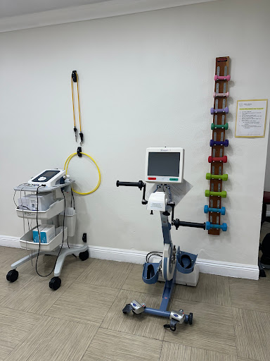 A view of a physical therapy room featuring an exercise bike and various weights.