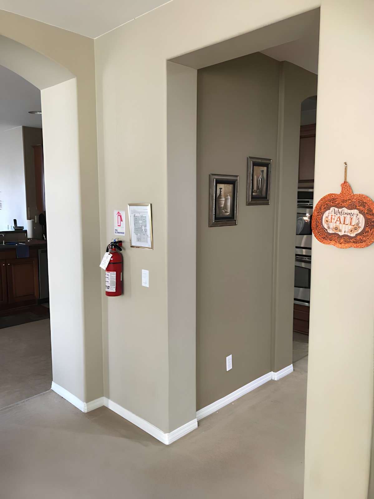 A cozy hallway featuring a fire extinguisher, wall art, and a pumpkin-themed decoration.