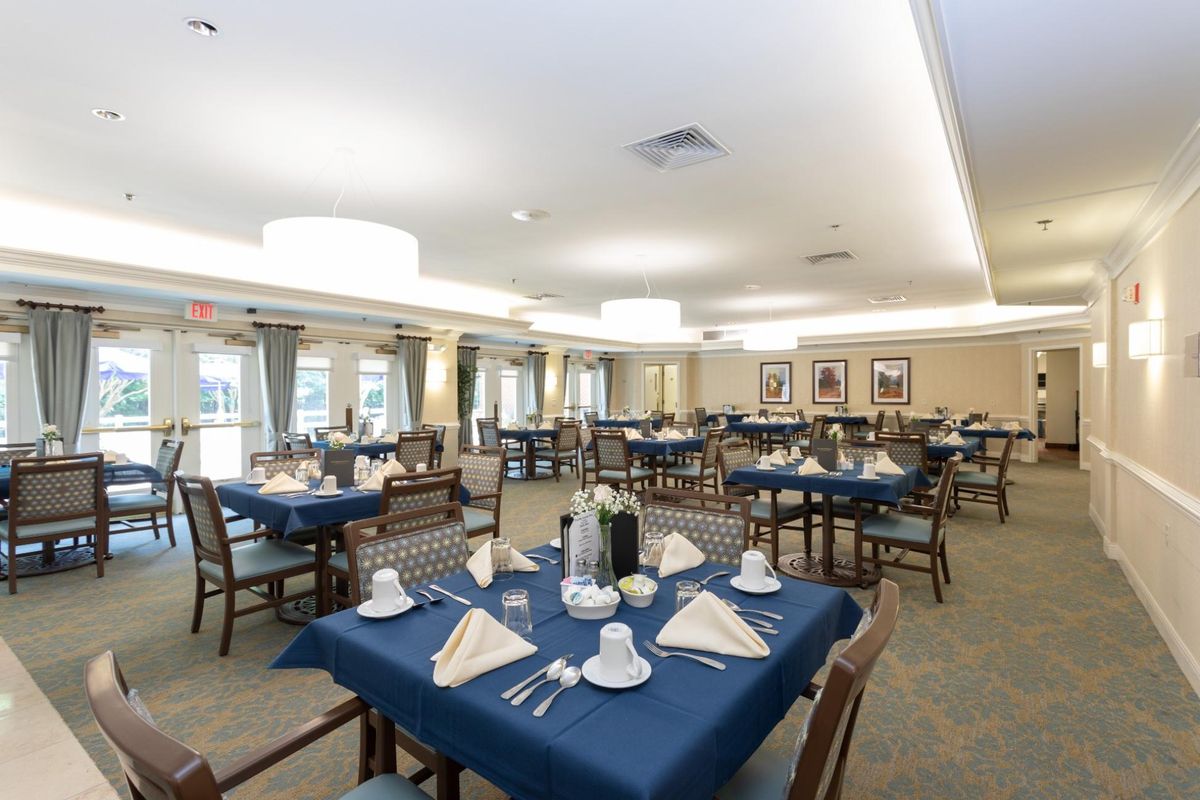 An elegant dining room with neatly set tables, featuring blue tablecloths and folded napkins.