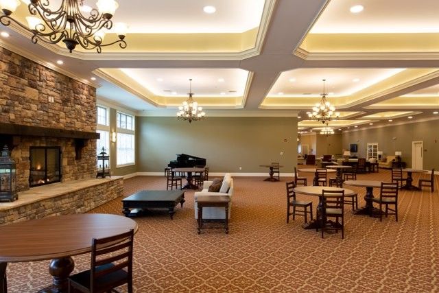 A spacious lounge area featuring a piano, multiple seating arrangements, and elegant chandeliers.