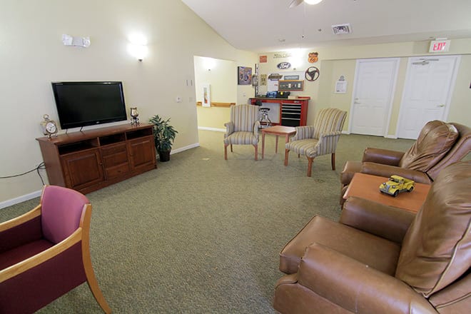 A cozy living room with seating area featuring sofas, chairs, a television, and a carpet.