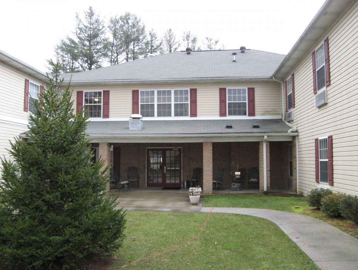 A two-story residential building with an entrance and surrounding greenery.