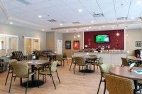 A modern cafe interior with tables, chairs, and a television on the wall.