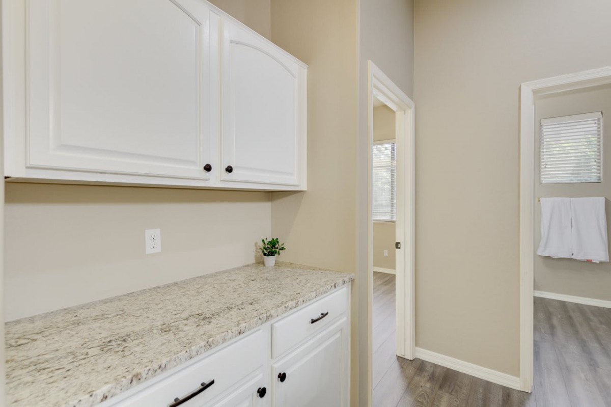 A modern kitchen interior featuring white cabinets and a granite countertop.