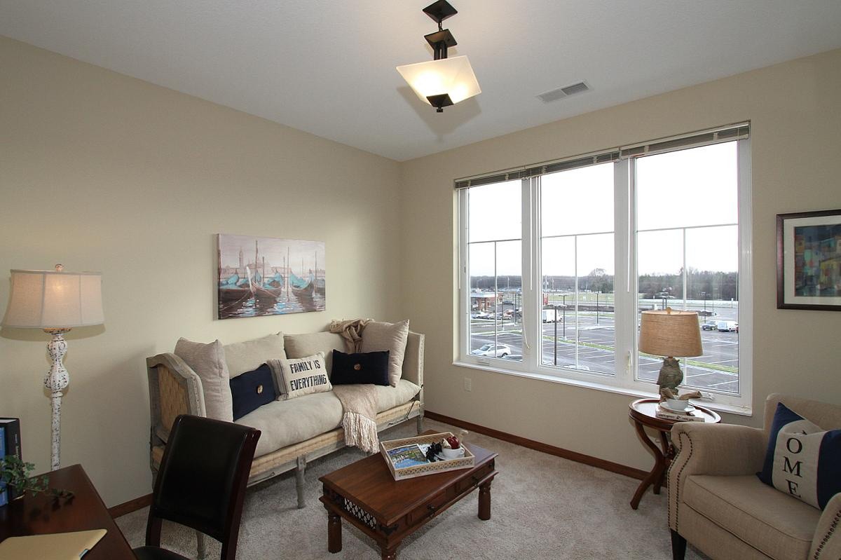 A cozy living room with a sofa, coffee table, and large window providing natural light.