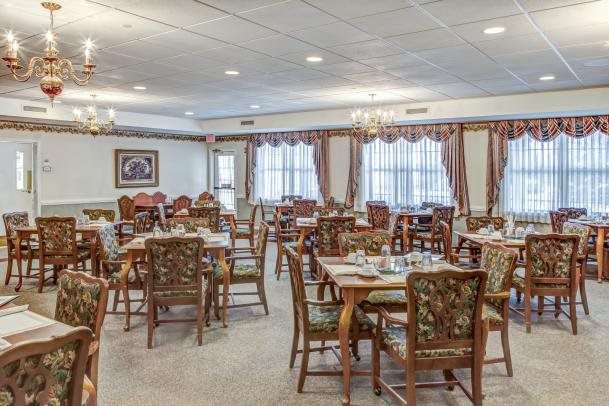An elegant dining area with neatly arranged tables and chairs, featuring classical decor and lighting.