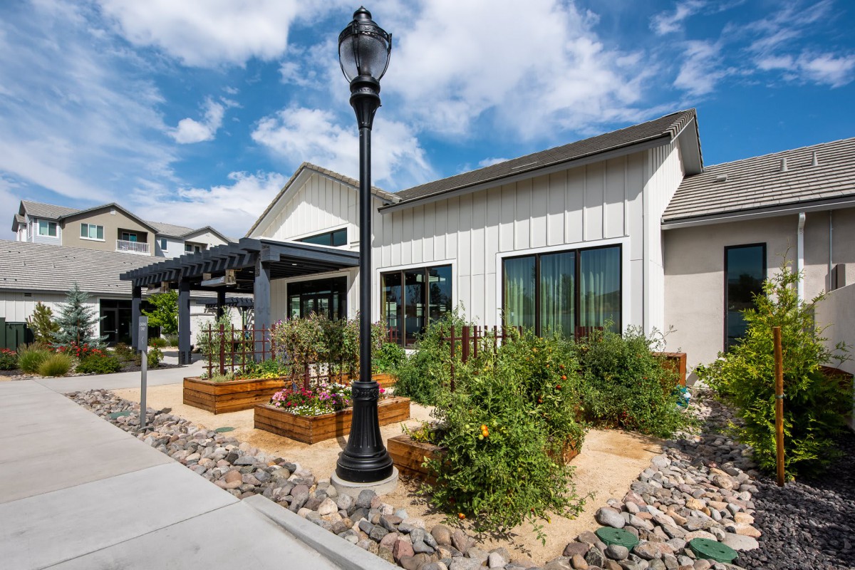 A modern house exterior with a landscaped garden featuring raised beds and a lamppost.