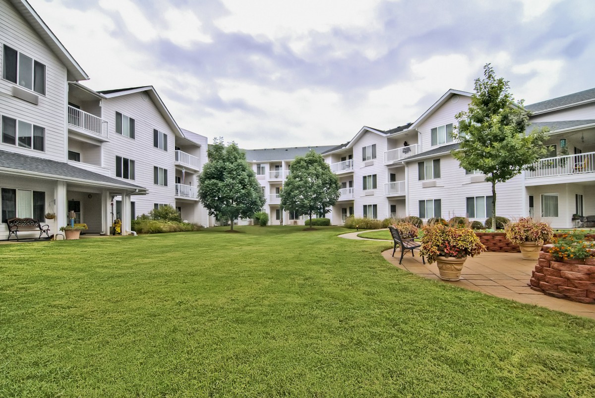 A courtyard with a grassy lawn surrounded by a three-story apartment building.
