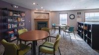 A conference room with multiple tables and chairs, a fireplace, and a window.