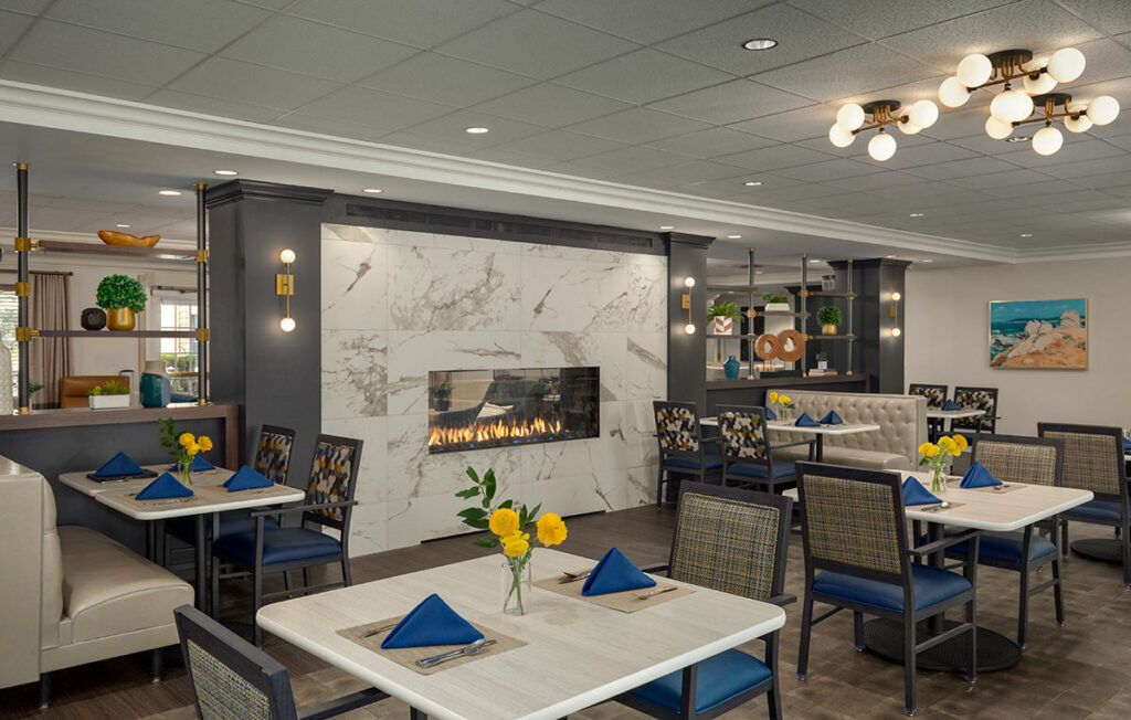 A modern restaurant dining area with marble decor and a cozy fireplace.